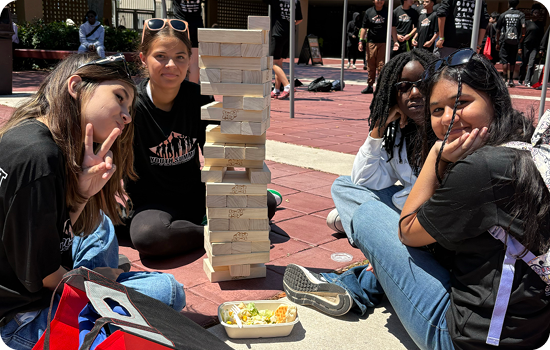 teens sitting together in a courtyard playing jenga